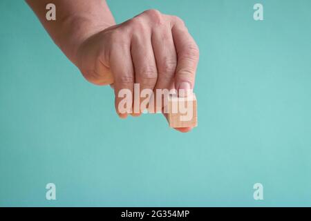 Hand hält ein Stück leeren Holzblock. Auf blauem Hintergrund Platz kopieren. Stockfoto