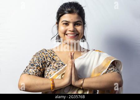 Eine schöne indische Frau in Saree isoliert auf weißem Hintergrund begrüßt in namaste Pose mit lächelndem Gesicht Stockfoto