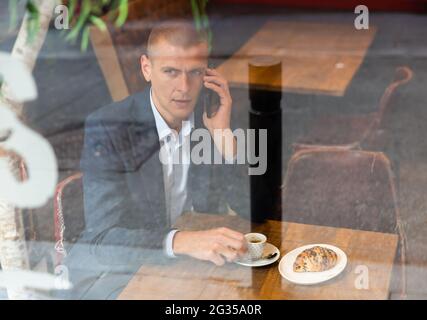 Geschäftsmann, der im Café sitzt und telefoniert Stockfoto