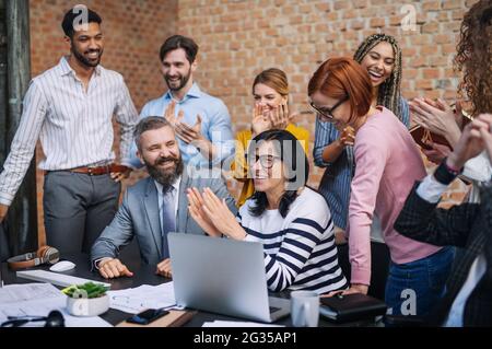 Gruppe von Unternehmern, die im Büro an einem Projekt arbeiten und einen erfolgreichen Vertrag feiern. Stockfoto