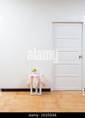 Zimmereinrichtung mit Tisch, weißer Tür und Holzboden. Hintergrund innen Stockfoto