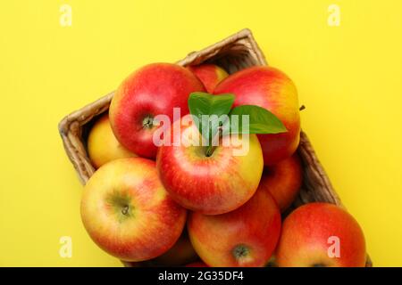 Korb mit roten Äpfeln auf gelbem Hintergrund Stockfoto