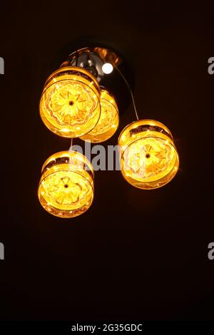 Foto einer leuchtend orange-gelben Laterne in der Nacht, aufgenommen bei schwachem Licht in der Dunkelheit mit Tiefenwirkung Stockfoto