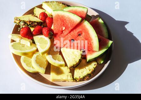 Teller mit frischen Früchten auf weißem Tisch, harte Schatten. Draufsicht. Stockfoto