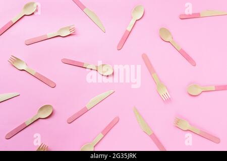 Textur von Einweg-Bambuslöffeln, Gabeln und Messern auf rosa Hintergrund. Zero Waste Konzept. Draufsicht, flach liegend.
