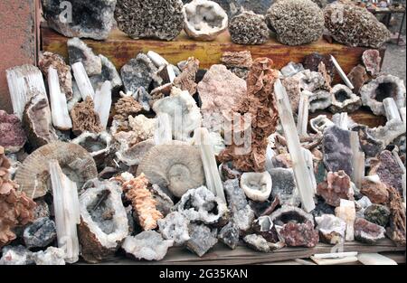 Traditionelle marokkanische Souvenirs - versteinerte Muscheln von Ammoniten, Quarzkristalle, Mineralien, fossiler Stromatolit, Straßenmarkt (Souk) in ESS Stockfoto