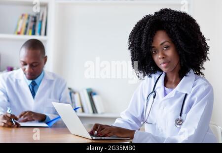 afroamerikanische Medizinstudentin, die mit einem männlichen Wissenschaftler im Krankenhaus am Computer arbeitet Stockfoto