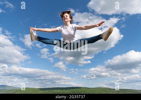 Voller Energie. Turnerin erwärmt sich auf dem Hintergrund des Himmels. Flexibilität. Stockfoto