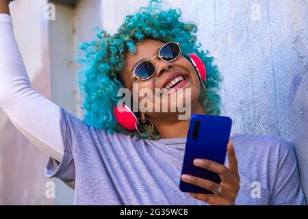 Lächelndes afro amerikanisches Mädchen mit Handy und Kopfhörer Stockfoto