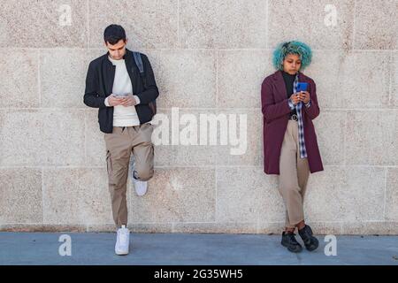 Junges Paar, das auf der Straße Telefone ansieht Stockfoto