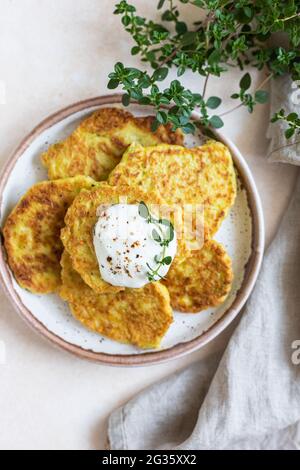 Gemüsefritter oder Pfannkuchen mit Joghurt oder saurem Dressing und Kräutern. Kohl oder Zucchini-Krapfen auf Keramikplatte. Gesundes vegetarisches Essen. Stockfoto
