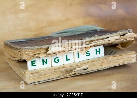 Auf dem Tisch stehen Buch- und Holzwürfel mit der Aufschrift englisch. Das Konzept des Lernens von Fremdsprachen. Stockfoto
