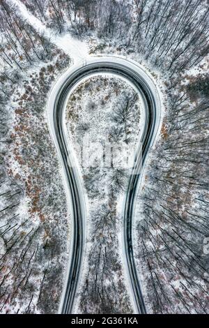 Kekesteto, Ungarn - Luftaufnahme der kurvigen Straße, die das Hufeisen von Matra (Matrai patko) in schneebedecktem Wald genannt wird, von oben nach unten Luftaufnahme Stockfoto