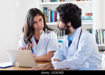 Junge arabische Ärztin im Gespräch mit einem männlichen Arzt über den Patienten im Krankenhaus Stockfoto