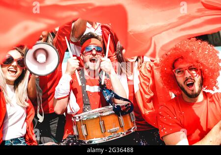 Fußballfans jubeln mit Flagge beim Fußballpokal-Spiel an der Tribüne des Stadions an - Junge Leute Gruppe mit rotem T-Shirt, die Spaß gemacht haben Stockfoto