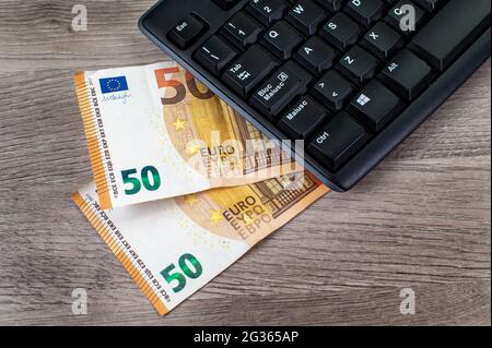 50 Euro Scheine und Computertastatur auf Holzhintergrund Stockfoto