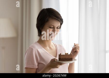 Nahaufnahme lächelnd schöne Frau, die Kuchen isst und Nachtisch genießt Stockfoto