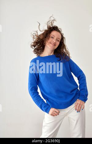 Junge weibliche Modell in trendigen Oversize blau Wolle Sweatshirt Blick auf die Kamera vor weißem Hintergrund Stockfoto