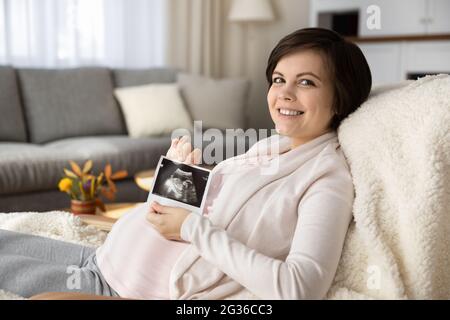 Porträt einer lächelnden Schwangeren mit Ultraschallbild Stockfoto