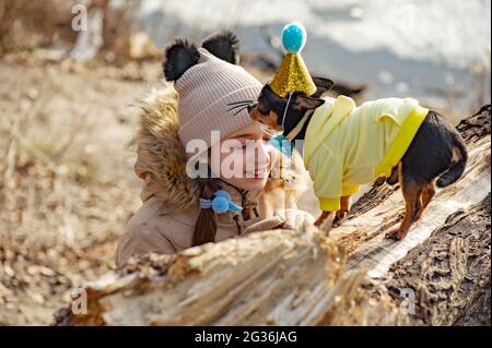 Außenportrait eines 10- 11-jährigen Mädchens in warmer beigefarbener Jacke mit einem chihuahua Hund. Geburtstag Stockfoto