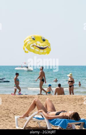 Antalya, Türkei-11. September 2017: Junge Frau sonnt sich an einem heißen Sommertag in Antalya auf der Sonnenliege am Strand. Menschen, die Aktivitäten durchführen. Stockfoto