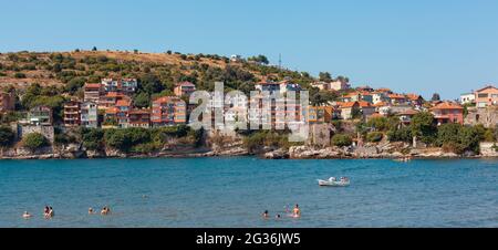 Amasra, Türkei-1. September 2011: Panoramablick auf Häuser in der Nähe der Küste, Menschen schwimmen, Sonnenbaden auf den Felsen im Sommer in Amasra. Stockfoto