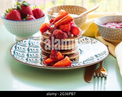 Vegane glutenfreie Bananenpfannkuchen mit Buchweizen, serviert mit milchfreiem Joghurt und Chia-Erdbeermarmelade Stockfoto