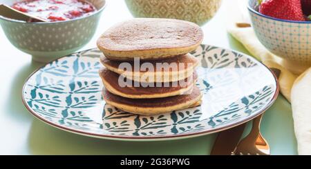 Vegane glutenfreie Bananenpfannkuchen mit Buchweizen, serviert mit milchfreiem Joghurt und Chia-Erdbeermarmelade Stockfoto