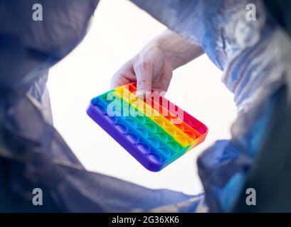 Sensorisches Anti-Stress-POPIT wird zur Entsorgung in den Müll geworfen. Nahaufnahme. Stockfoto