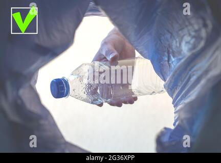 Die Plastikflasche wird in den Müll geworfen. Ein grünes Häkchen mit Leerzeichen zum Einfügen von Text. Nahaufnahme Stockfoto