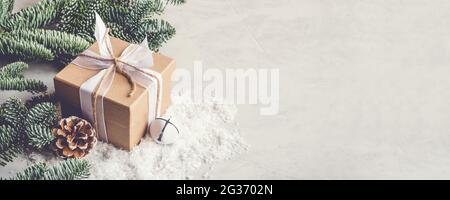 Weihnachts-Geschenkbox im Schnee auf grauem Hintergrund. Stockfoto