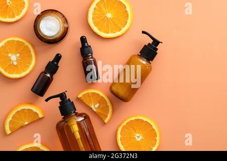 Bernsteinfarbene Glasflaschen mit Vitamin C-Kosmetik und in Scheiben geschnittener orangefarbener Ansicht von oben. Design von Naturkosmetischen Produkten. Stockfoto