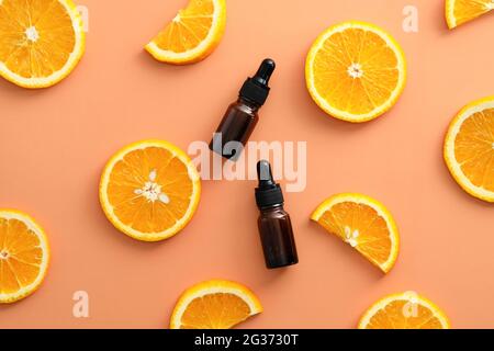 Braune Tropfflaschen aus Vitamin C-Bernsteinglas und in Scheiben geschnittene orangefarbene Draufsicht. Markenbezeichnung für Naturkosmetik. Stockfoto