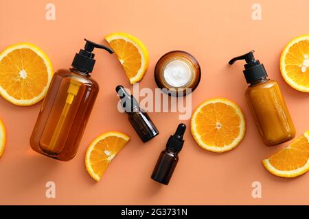 Flaches Vitamin-C-Serum in Tropfflaschen, Glas oder Creme, Duschgel, Shampoo mit Orange in Scheiben. Draufsicht natürliche Fruchtkosmetik. Stockfoto