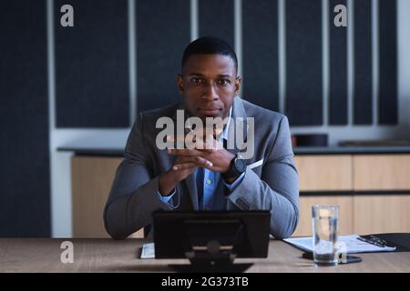 Porträt eines afroamerikanischen Geschäftsmannes, der im Besprechungsraum eines modernen Büros sitzt Stockfoto
