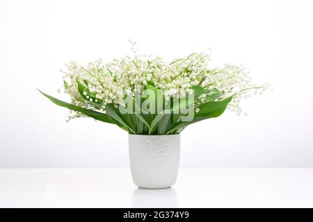 Ein Strauß weißer Blumen auf hellem Hintergrund. Maiglöckchen in einer weißen Vase. Stockfoto