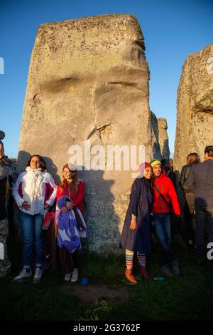 Nachtschwärmer feiern die Sommersonnenwende unter den alten Steinen des neolithischen Denkmals Stonehenge auf der Salisbury Plain, England, Großbritannien. Stockfoto