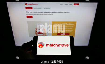 Person, die Mobiltelefon mit dem Logo des singapurischen Fintech-Unternehmens MatchMove Pay Pte. Ltd. Auf dem Bildschirm vor der Webseite hält. Konzentrieren Sie sich auf die Telefonanzeige. Stockfoto