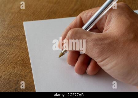 Männliche Hand mit Stift auf einem leeren Blatt Papier schreiben Stockfoto