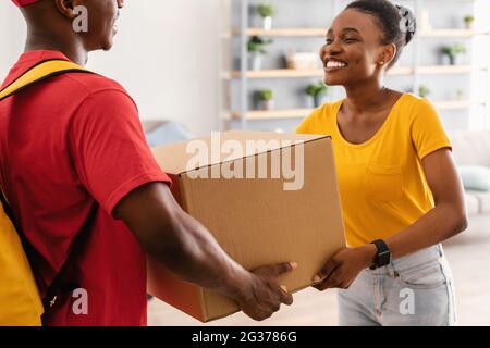 Glückliche Afroamerikanische Frau Erhält Box Von Courier Zu Hause Stockfoto