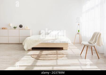 Bett mit Kissen, Teppich auf Holzboden, Fenster mit Vorhängen, Möbel Stockfoto