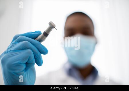 Nahaufnahme Des Schwarzen Arztes Des Zahnarztes In Der Medizinischen Maske, Die Zahnbohrmaschine Hält Stockfoto