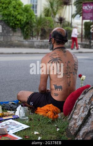 Tätowierte Rückseite des Klimaprotesten in Falmouth während des G7-Gipfels in Cornwall. Unter einem Baum sitzend, umgeben von Blumen und Stückchen. Stockfoto