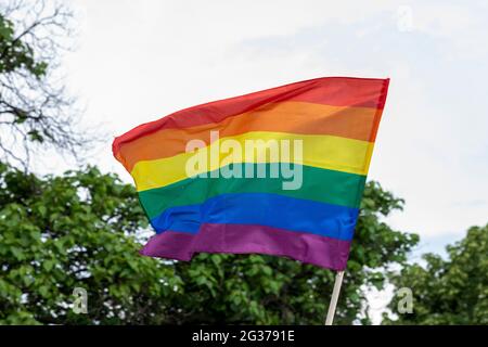 Die Flagge auf der Gay Pride Parade, die Rainbow-Flagge, ein Symbol für die LGBT-Gemeinschaft, winkt im Wind mit einem bewölkten Hintergrund Stockfoto