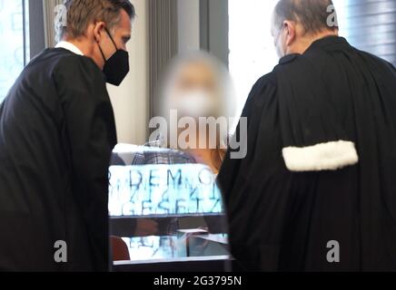 Wuppertal, Deutschland. Juni 2021. Die Angeklagte Mutter (M) steht zwischen ihren Anwälten Felix Menke (l) und Thomas Seifert (r) im Gerichtssaal - das Wort "Gesetz" spiegelt sich aus dem Fenster in einer Scheibe, die wegen Corona angebracht ist. Im Fall der fünf im Nordrhein-westfälischen Solingen getöteten Kinder hat der Mordprozess gegen ihre Mutter vor dem Landgericht Wuppertal begonnen. Quelle: Oliver Berg/dpa - ACHTUNG: Der Angeklagte wurde aus rechtlichen Gründen verpixelt/dpa/Alamy Live News Stockfoto