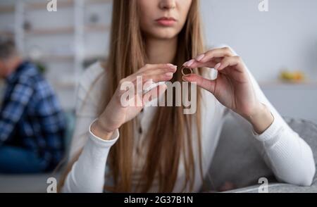 Beschnittene Ansicht der verärgerten reifen Frau, die ihren Ehering auszieht, die Scheidung mit ihrem Mann zu Hause plant, Nahaufnahme Stockfoto