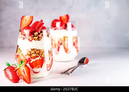 Gesundes Frühstück mit Erdbeerparfaits aus frischer Erdbeere, Joghurt und Müsli in Gläsern. Stockfoto