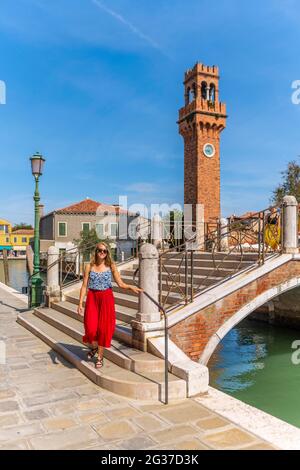 Junge Frau an einem Kanal, Häuser und Boote am Kanal Rio del Vetrai, Glockenturm St. Stefano, Murano, Venedig, Venetien, Italien Stockfoto