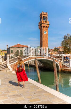 Junge Frau an einem Kanal, Häuser und Boote am Kanal Rio del Vetrai, Glockenturm St. Stefano, Murano, Venedig, Venetien, Italien Stockfoto