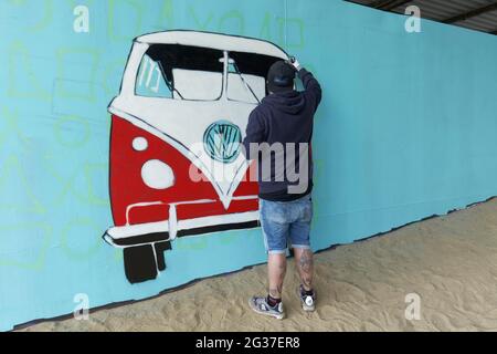 Graffitimaler sprüht VW-Bus, Bulli, auf eine blau grundierte Wand, Duisburg, Nordrhein-Westfalen, Deutschland Stockfoto